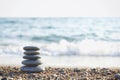 Zen pyramid of spa stones on the blurred sea background. Sand on a beach. Sea shores. Water waves texture. Left side of photo. Pla Royalty Free Stock Photo