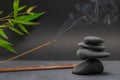 Zen spa basalt stones and green bamboo leaves and incense on black background. Royalty Free Stock Photo