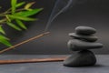 Zen spa basalt stones and green bamboo leaves and incense on black background. Royalty Free Stock Photo