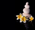 Zen stone pyramid with three white gentle frangapani plumeria flowers after rain on the black reflective background. Low key2