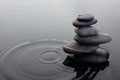 Zen stones in balanced pile in water on rippled water surface.