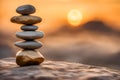 Zen stones stacked forming a pyramid on a rock, against the backdrop of the sunset, symbolizing harmony.