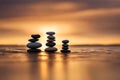 Zen stones stacked forming a pyramid on rocks, against the backdrop of the sunset, symbolizing harmony.