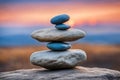 Zen stones stacked forming a pyramid on rocks, against the backdrop of the sunset, symbolizing harmony.