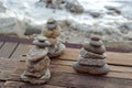 Three piles of Zen stones on a wooden floor at the Atlantic ocean sandy beach.