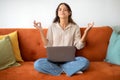 Zen. Woman Sitting On Couch With Laptop And Meditating With Eyes Closed Royalty Free Stock Photo