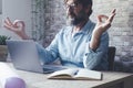 Zenlike meditation person relaxing sitting in front of a laptop computer at the desk in home office workplace. Healthy mental Royalty Free Stock Photo