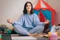 Carefree Mother Sitting in Lotus Position Surrounded by Toys Royalty Free Stock Photo