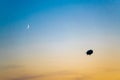 Zeppelin in evening sky with crescent moon. Airship in backlight in bright sky. Zeppelin in sky during sunset with crescent moon.. Royalty Free Stock Photo