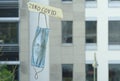 Zero covid sign and old surgical mask on window, office buildings in the back