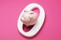 Zero and piggy bank on a pink background. Concept on the topic of zeroing deposits Royalty Free Stock Photo