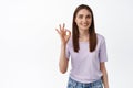 Zero problems, alright. Young smiling woman shows okay OK sign and nod in approval, like and agree gesture, approve