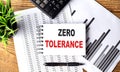 ZERO TOLERANCE text on a notebook with chart and calculator