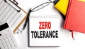 ZERO TOLERANCE text on notebook with clipboard and calculator on white background