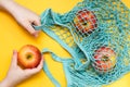 Zero waste concept. Children`s hands stack ripe apples in a cotton mesh bag. Top view