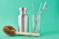 Zero waste concept. Eco friendly reusable items aluminun bottle and metal tubes in glass on a green background