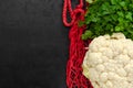 Zero waste concept. Red net bag, raw white cauliflower, fresh green parsley on black background. Eco friendly lifestyle Royalty Free Stock Photo