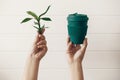 Zero waste concept, sustainable lifestyle. Hands holding stylish reusable eco coffee cup and green bamboo leaves on white wooden Royalty Free Stock Photo