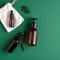 Zero waste organic SPA cosmetics set with green leaves. Top view amber glass bottles on green background. Natural skincare beauty