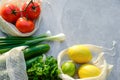 Zero waste shopping concept. Fresh vegetable and fruits in eco friendly cotton bags on stone table. Top view, flat lay tomatoes,