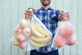 Zero waste shopping concept. Smiling man holding reusable eco bags with fresh fruits. Ban single use plastic Royalty Free Stock Photo