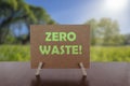 Zero waste text on card on the table with sunny green park background. Ecology concept, recycle, reuse, reduce waste Royalty Free Stock Photo