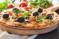 Flatbread pizza garnished with fresh arugula on wooden pizza board, top view. Dark stone background. Person picking slice of pizza