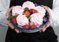 Zhenschina holds a Plate with homemade marshmallows, decorated with berries. No face. Bakery advertising concept, cooking secrets