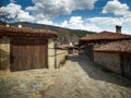 Zheravna, Bulgaria - narrow cobbled road and rustic traditional houses made of stone and wood with bigroot cranesbill Royalty Free Stock Photo