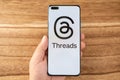 hand holding a mobile with Threads logo at horizontal composition