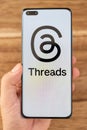 hand holding a mobile with Threads logo at vertical composition