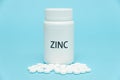 ZINC in white bottle packaging with scattered pills. Nutritional supplement. Treatments for COVID-19. isolated on blue background Royalty Free Stock Photo