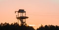 Zipline tower with people silhouettes at sunset