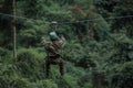 zipliner with a camouflaged outfit blending into a green forest Royalty Free Stock Photo