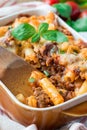 Ziti bolognese in baking dish. Pasta casserole with minced meat, tomato sauce and cheese, vertical