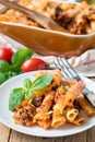 Ziti bolognese on white plate, pasta casserole with minced meat, tomato sauce and cheese, vertical