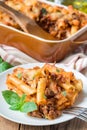 Ziti bolognese on white plate, pasta casserole with minced meat, tomato sauce and cheese, vertical