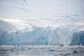 Zodiac - tiny beside immense ice cliffs - explores Paradise Bay, Antarctica