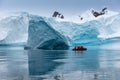 A zodiac full of tourists viewing amazing icebergs and glaciers in Antarctica.