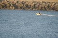 Zodiac sailing in the sea next to a breakwater.