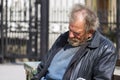 Zolochiv, Ukraine - April 10, 2018: Homeless man sitting asleep
