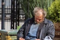 Zolochiv, Ukraine - April 10, 2018: Homeless tramp sitting asleep