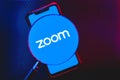 Zoom app logo on the screen smartphone under a magnifying glass