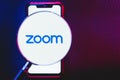 Zoom app logo on the screen smartphone under a magnifying glass