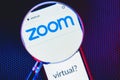 Zoom app logo on the screen smartphone under a magnifying glass