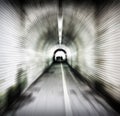 Zoom blur image of an old dark pedestrian tunnel with unidentifiable people emerging into the light