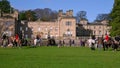 Zoom in on Horse riding fox hunters, a pack of English Foxhounds and a number of spectators gathered in front of a traditional