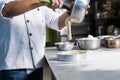 Zoom of pastry chef hand pouring batter from steel bowl to cake mold on stainless table