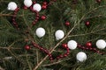 zoom on a pile of fir branches with a frame of bright red pearl garland and many christmas bauble red and white