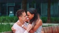 Zoom shot of young mixed-race couple stroking each other sitting outdoors.